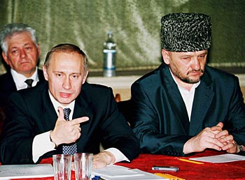 President Poetin wordt bij zijn ingelaste bezoek aan de basis Mozdok geflankeerd door Achmed Kadyrov, sinds kort leider van het pro-Russische bestuur van Tsjetsjenië. (Foto Reuters)